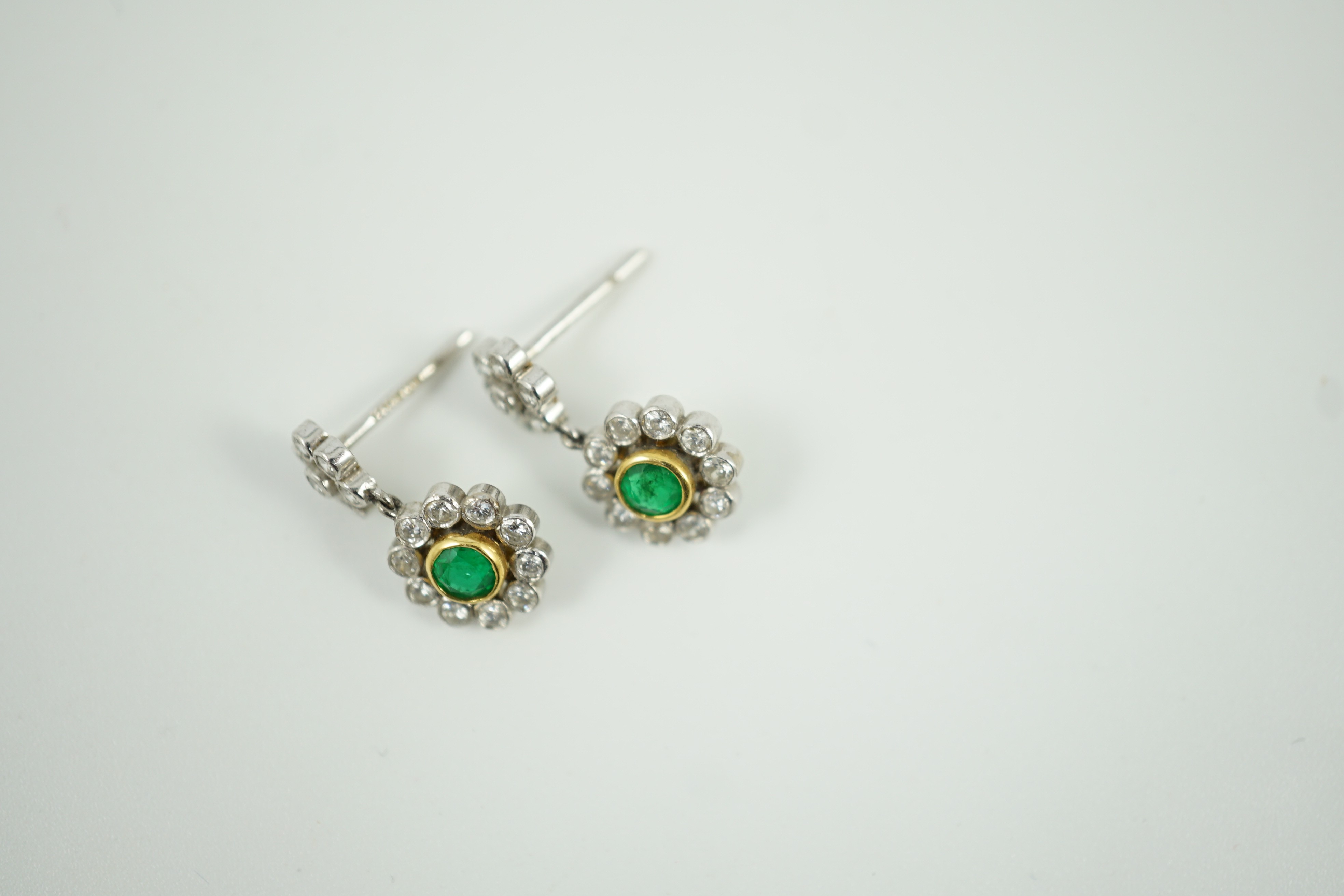 A modern pair of 18ct white gold, emerald and diamond cluster set drop earrings, 16mm, gross weight 3 grams.
